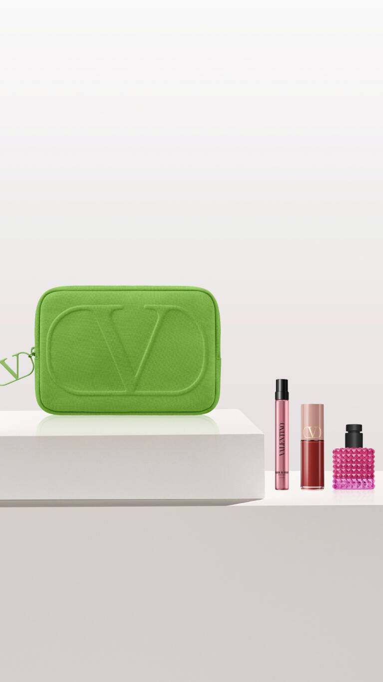 Groene toilettas met 'CD'-logo, omringd door cosmetica in roze en zwarte flessen op een witte ondergrond.